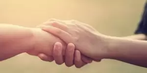 Imagem de duas pessoas com as mãos dadas, simbolizando a empatia como ferramenta da qualidade.
