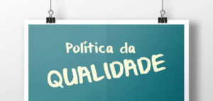 Imagem com um fundo branco e uma plaquinha azul pendurada com o escrito: Política da Qualidade