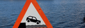 imagem com uma placa em que um carro está andando, porém, sinaliza que não há mais chão, e sim, mar. Essa imagem simboliza o artigo sobre gestão de mudanças abruptas.