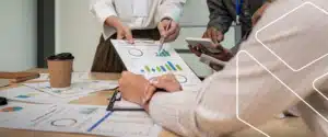 Profissionais analisando indicadores e dados em reunião sobre melhoria contínua e Sistema de Gestão da Qualidade conforme a ISO 9001:2015.