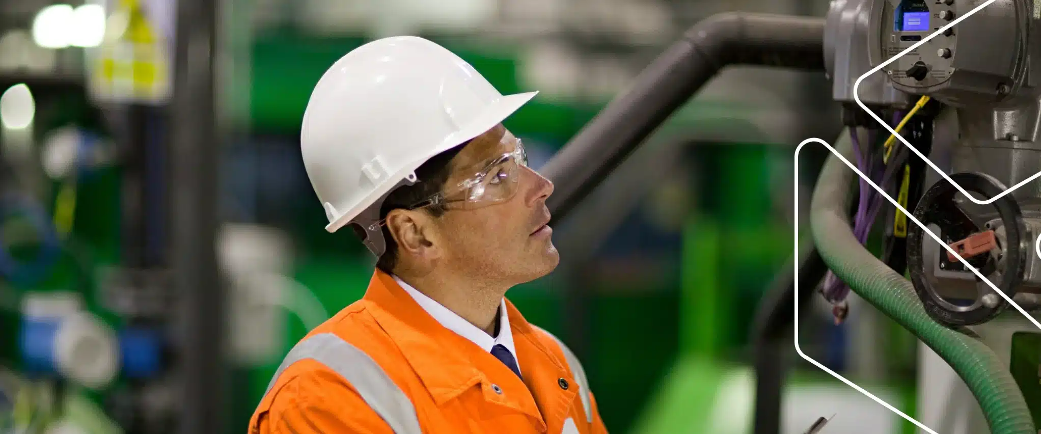 Inspetor da qualidade com capacete e óculos de proteção verificando um equipamento industrial e registrando a inspeção em uma prancheta